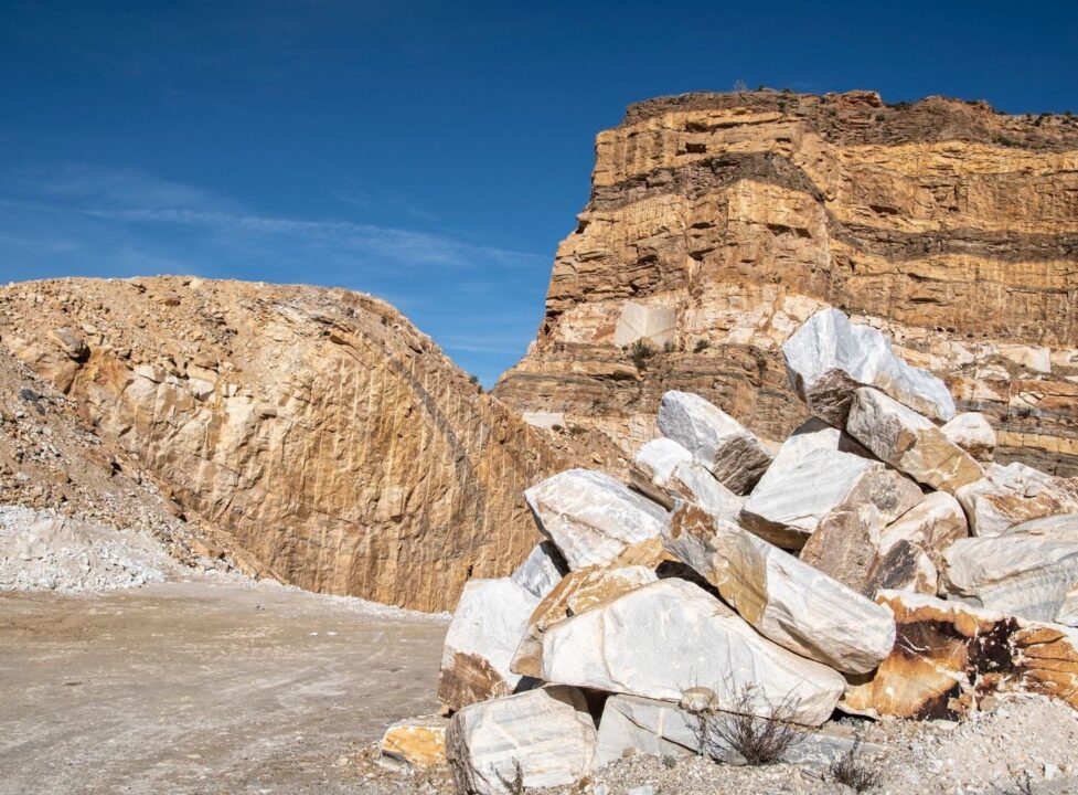 Öppet kalkstensbrott med skiktade bergväggar och stora brutna stenblock
