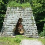 Historisk kalkugn av grovhuggna stenblock i en grönskande skog