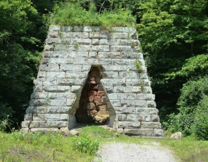 Historisk kalkugn av grovhuggna stenblock i en grönskande skog