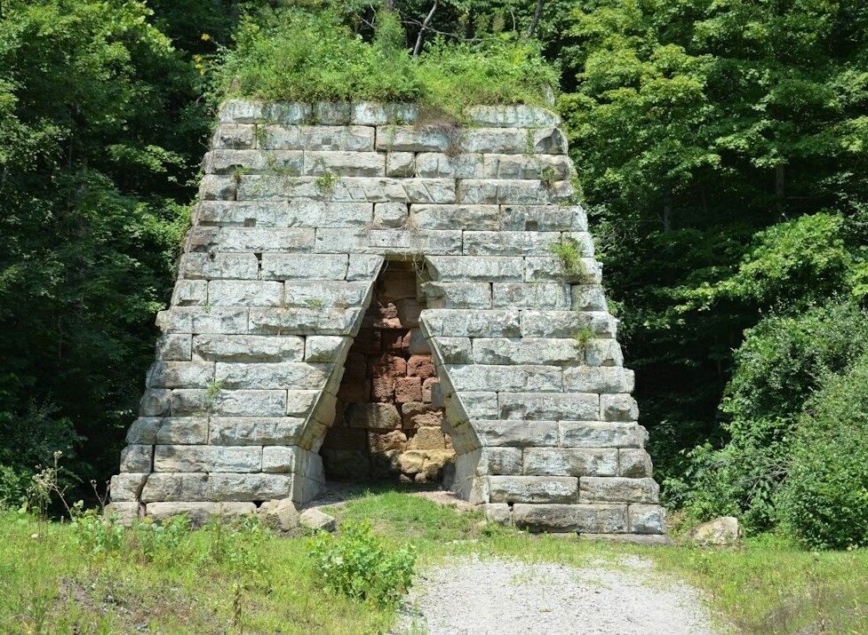 Historisk kalkugn av grovhuggna stenblock i en grönskande skog