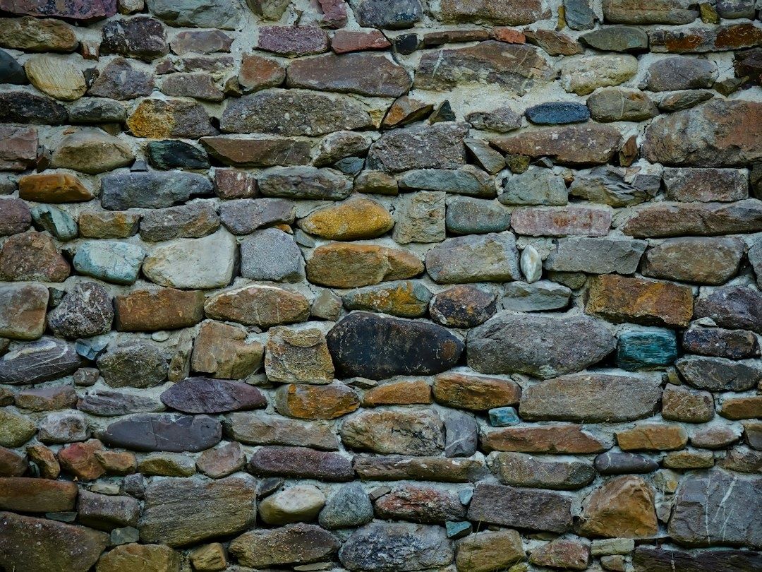 Närbild av en äldre stenmur med varierande natursten och fogar